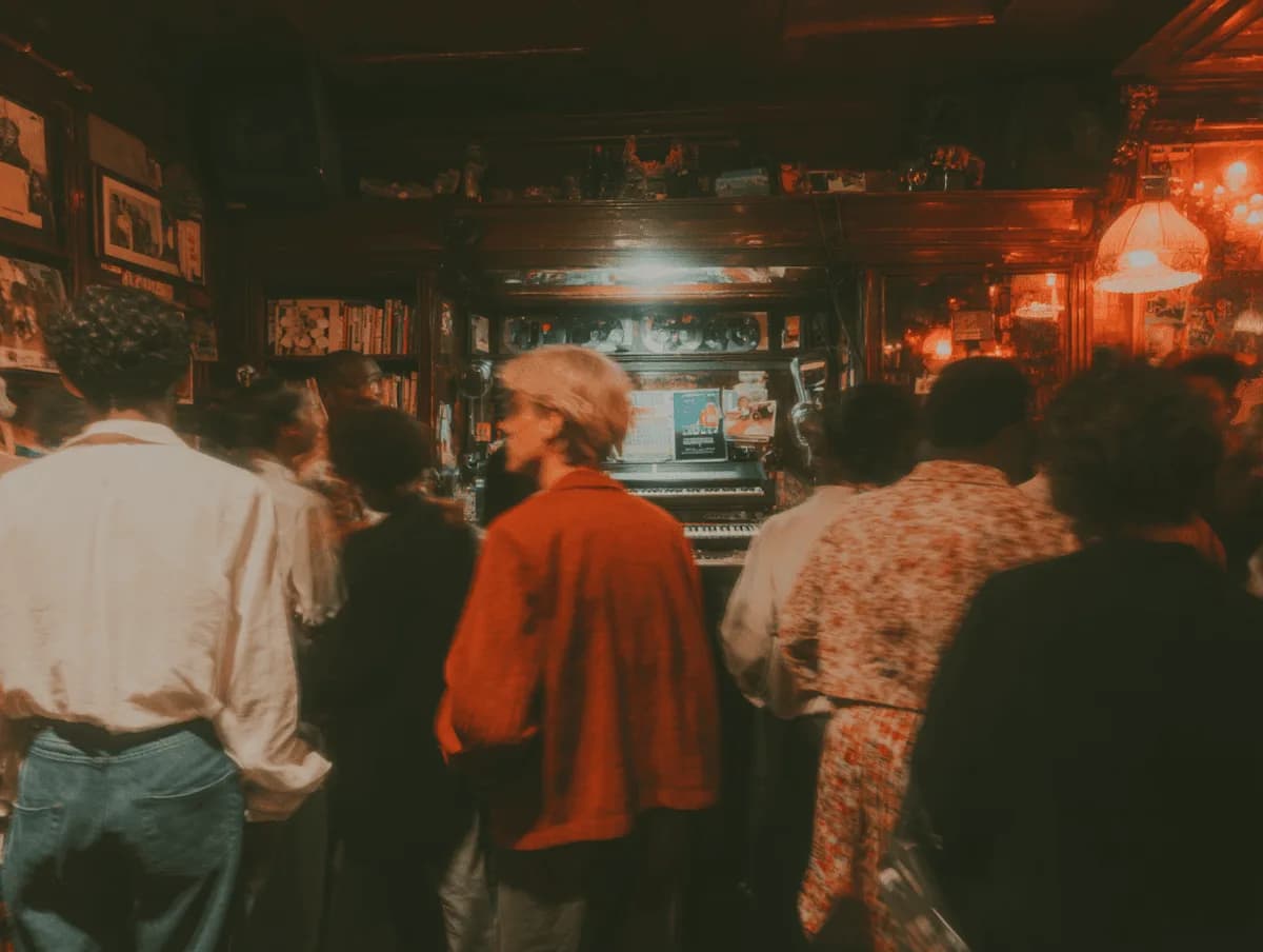 Gente en la barra de un bar lleno, iluminada con luz roja