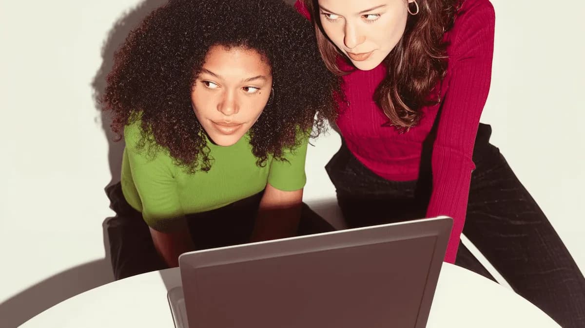 Dos mujeres miran juntas la pantalla de una notebook