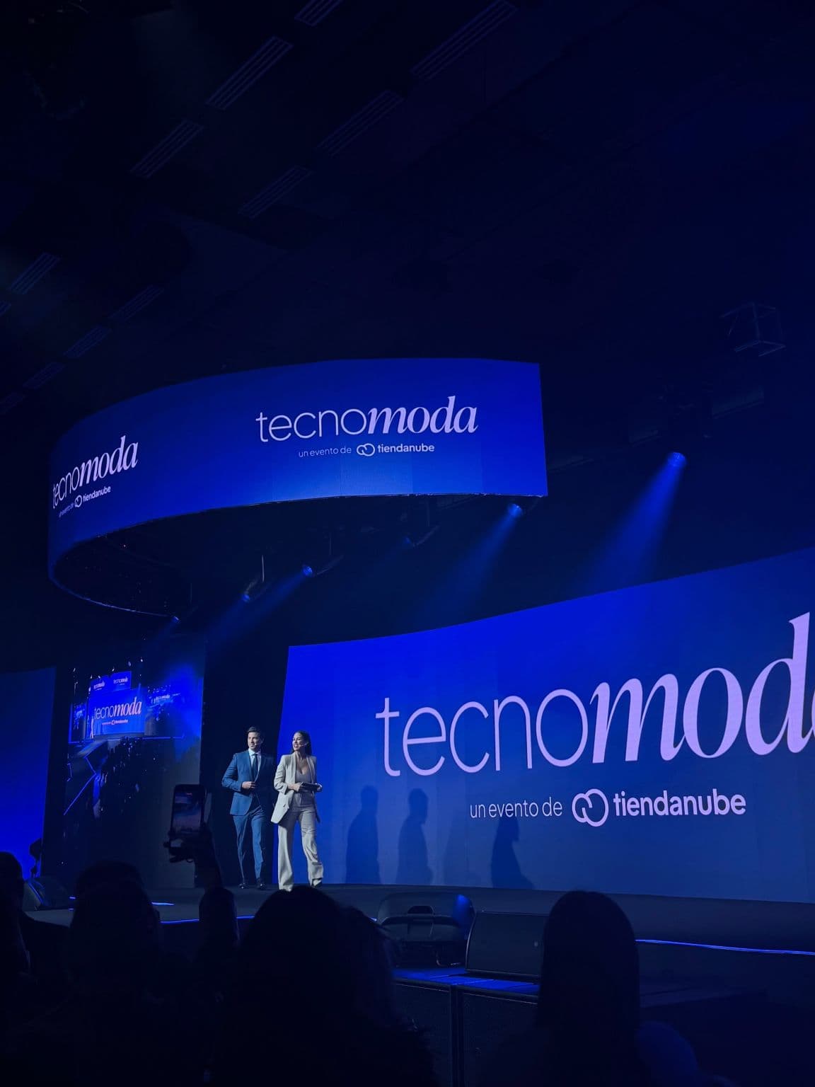 El escenario de Tecnomoda con la pantalla que dice “tecnomoda, un evento de tiendanube” y los presentadores entrando.