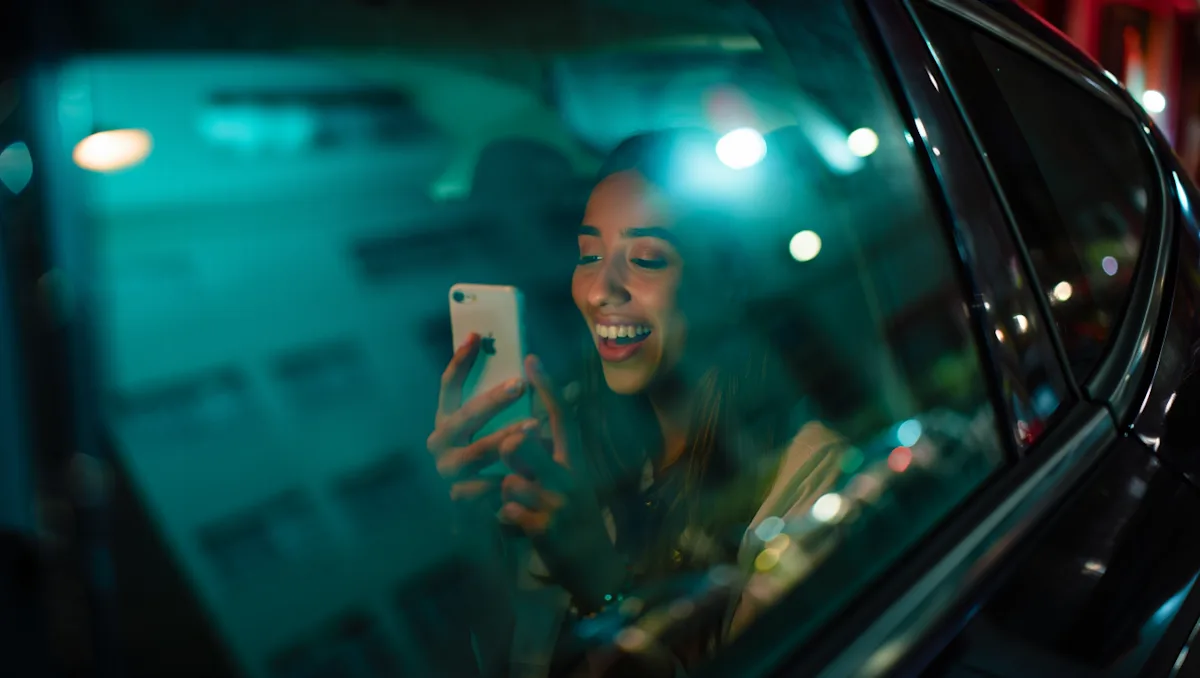Una mujer adentro de un auto mirando el teléfono y sonriendo.
