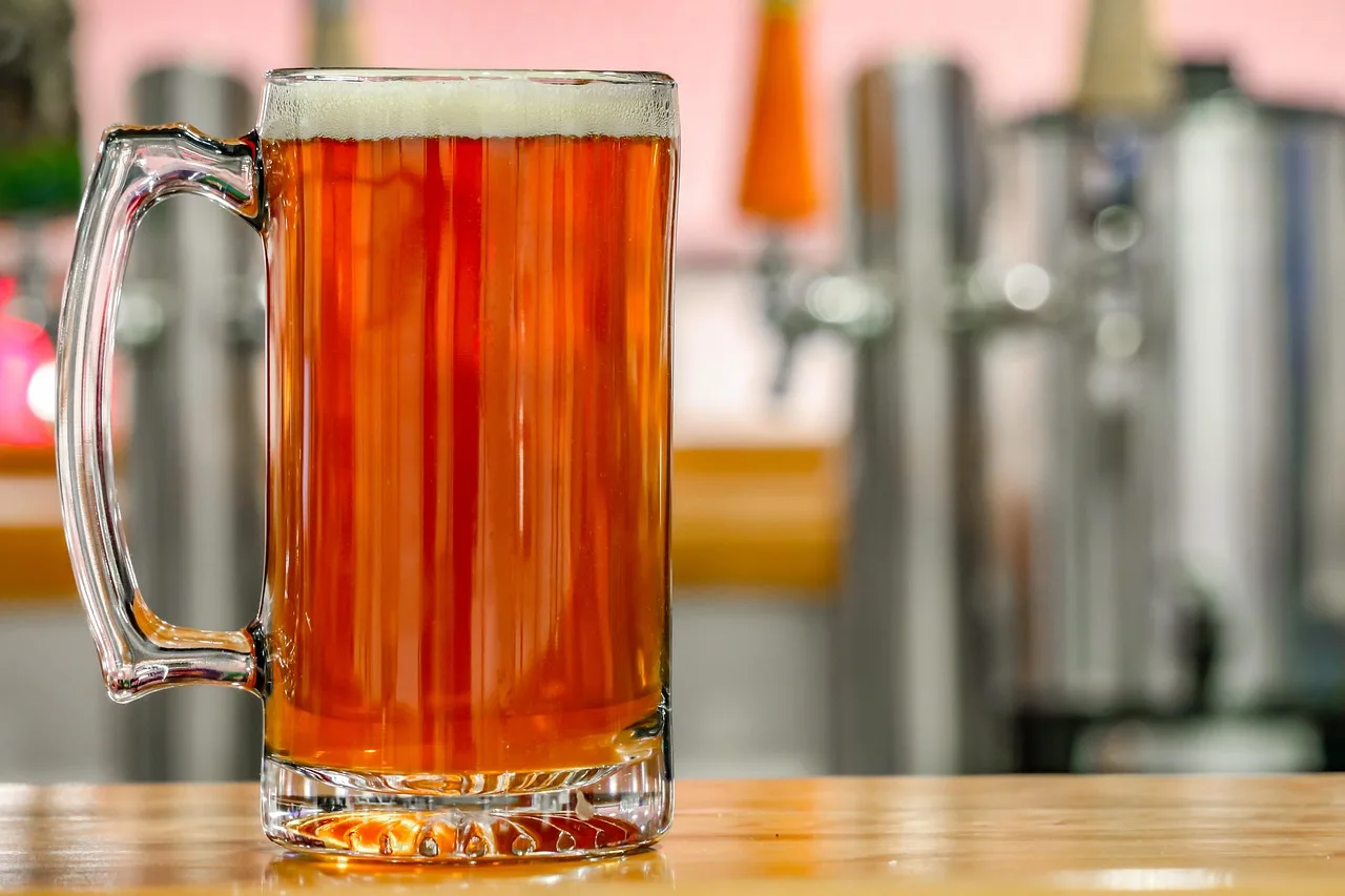 Un chopp de cerveza roja sobre una barra de madera, con las canillas desenfocadas de fondo