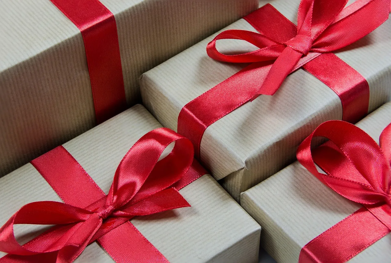Varias cajas envueltas en papel claro y atadas con moños de cinta roja, apiladas unas junto a otras